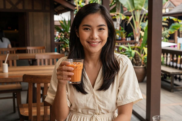 Young Thai woman enjoying Thai iced tea at an outdoor cafe in Chiang Mai, showcasing relaxed Thai dating culture